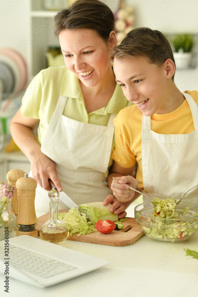 Mother and son making fresh salad at kitchen Mother and son making fresh salad at kitchen