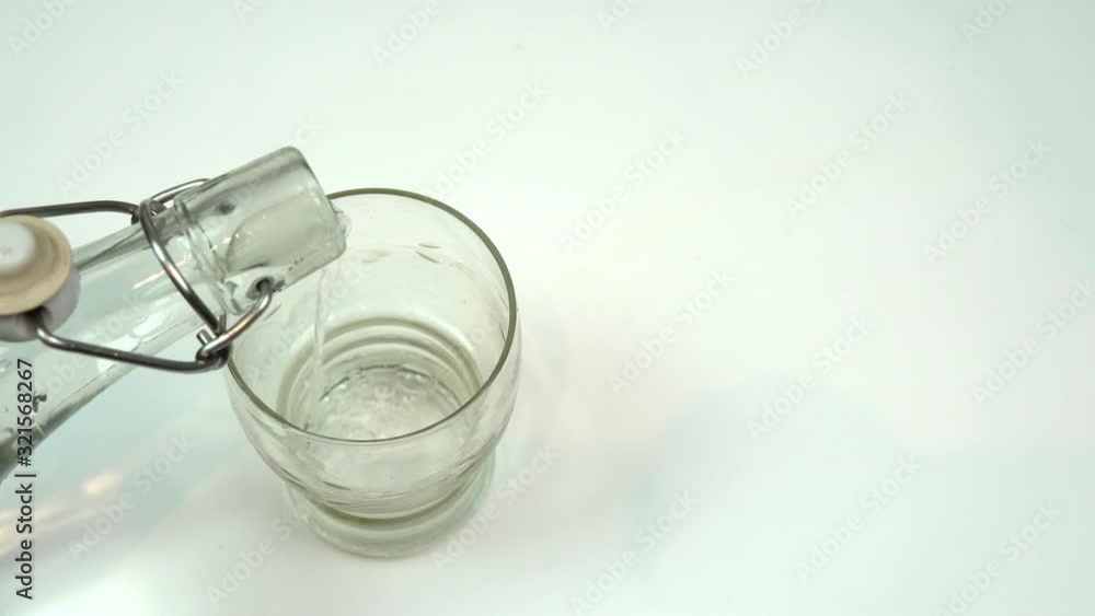 glass bottle filling glass of water, isolated on white background glass bottle filling glass of water, isolated on white background