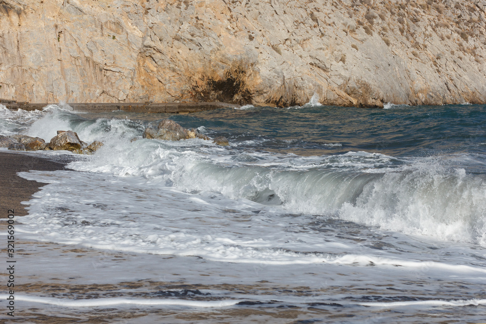 beaches with black volcanic sand and soft volcanic pebbles, with waves of white sea foam on the island of Santorini in Greece beaches with black volcanic sand and soft volcanic pebbles, with waves of white sea foam on the island of Santorini in Greece
