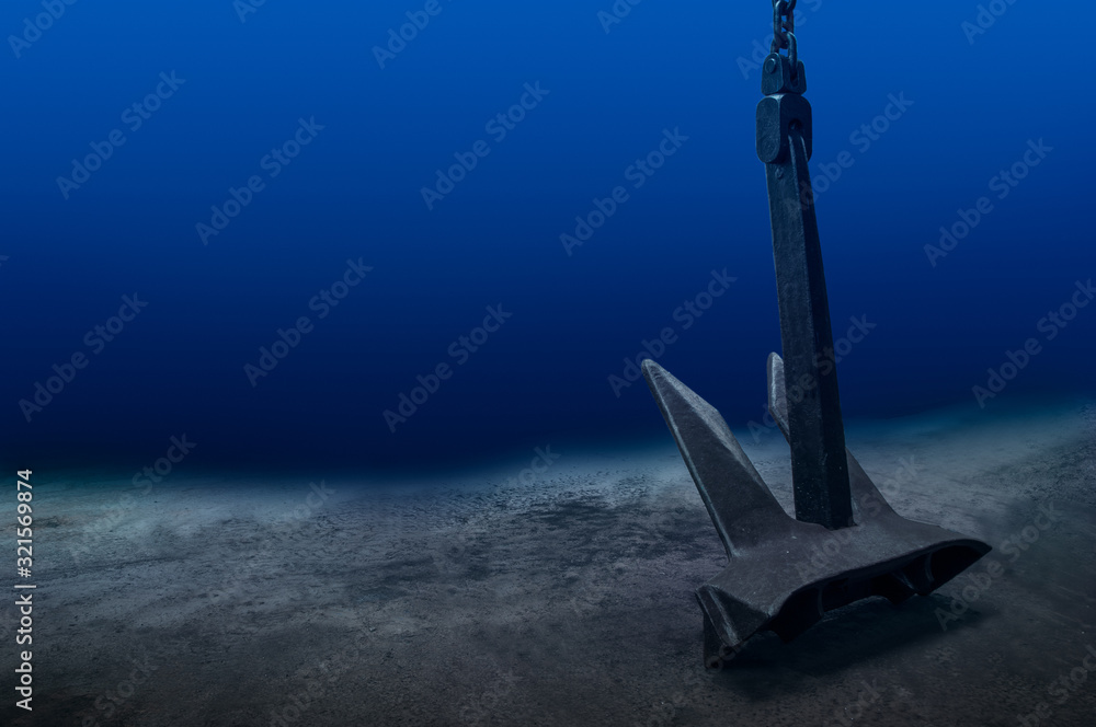 Ship anchor underwater on bottom in clean ocean water at anchorage