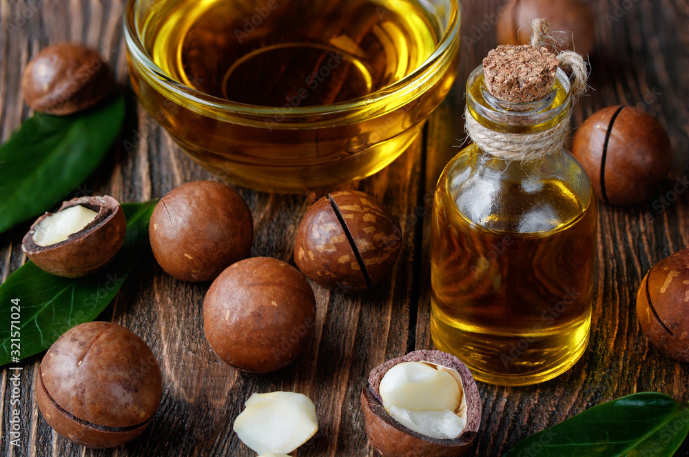 Organic macadamia oil and macadamia nuts for massage on wooden background. Organic macadamia oil and macadamia nuts for massage on wooden background.