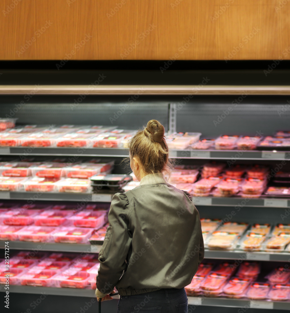 Woman purchasing a packet of meat at the supermarket	
