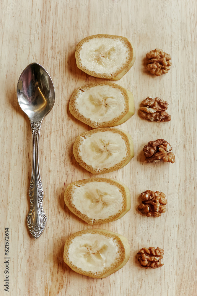 Sliced bananas with peeled walnuts spread out on a wooden table. Sliced bananas with peeled walnuts spread out on a wooden table.