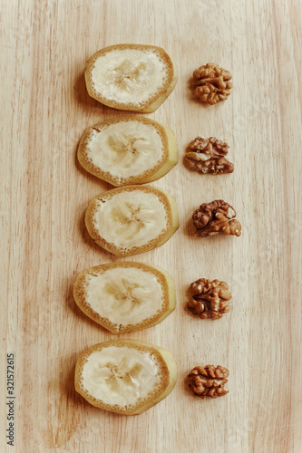 Fresh sliced bananas with walnuts on a wooden table.