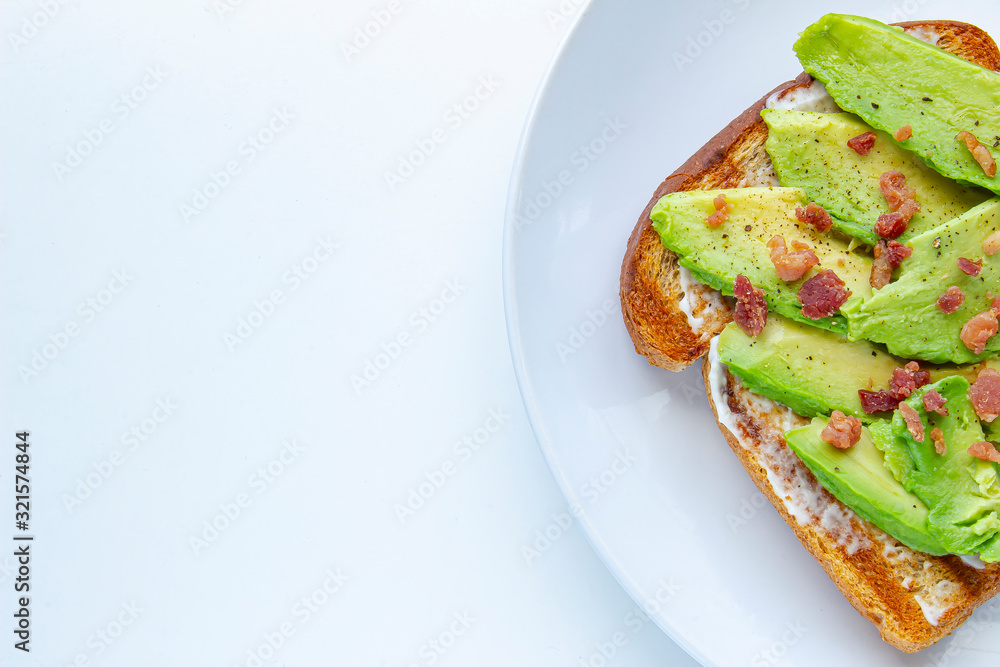 Close up of an avocado with bacon bites toast on a white plate on the right Close up of an avocado with bacon bites toast on a white plate on the right