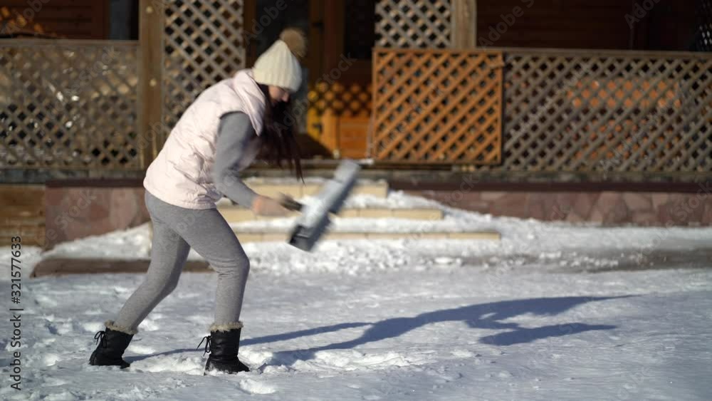 Young woman shoveling snow on backyard near the house . Young woman shoveling snow on backyard near the house .