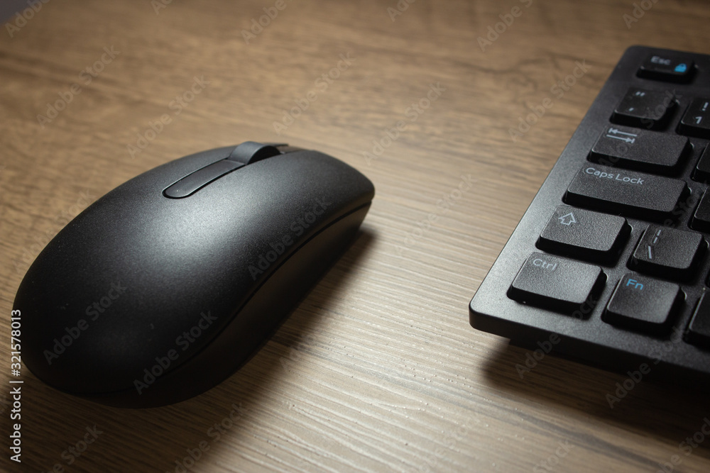 Wireless mouse and keyboard set on top of a wooden office desk, on a workstation Wireless mouse and keyboard set on top of a wooden office desk, on a workstation