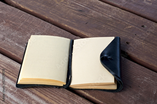 Photography An open leather bound black journal outdoors on table, revealing blank pages, with room for copy