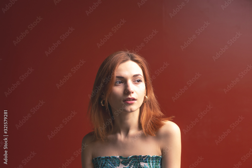 Red-haired girl on a red background shows different emotions Red-haired girl on a red background shows different emotions