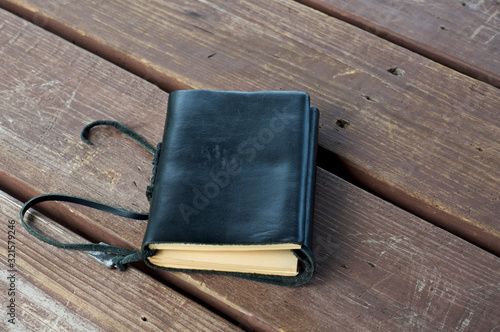 Canvas Print A closed leather bound black journal outdoors on table, with blank cover