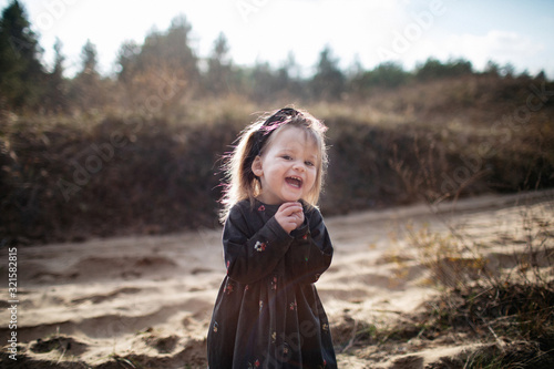 Close portrait of Cute little laughing girl posing at camera in autumn forest. photo