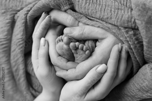 the legs of the child in the arms of the mother and the father the legs of a newborn baby . black and white photo