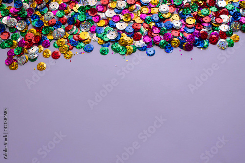 lentejuelas de colores de carnaval sobre marco de color lila  photo