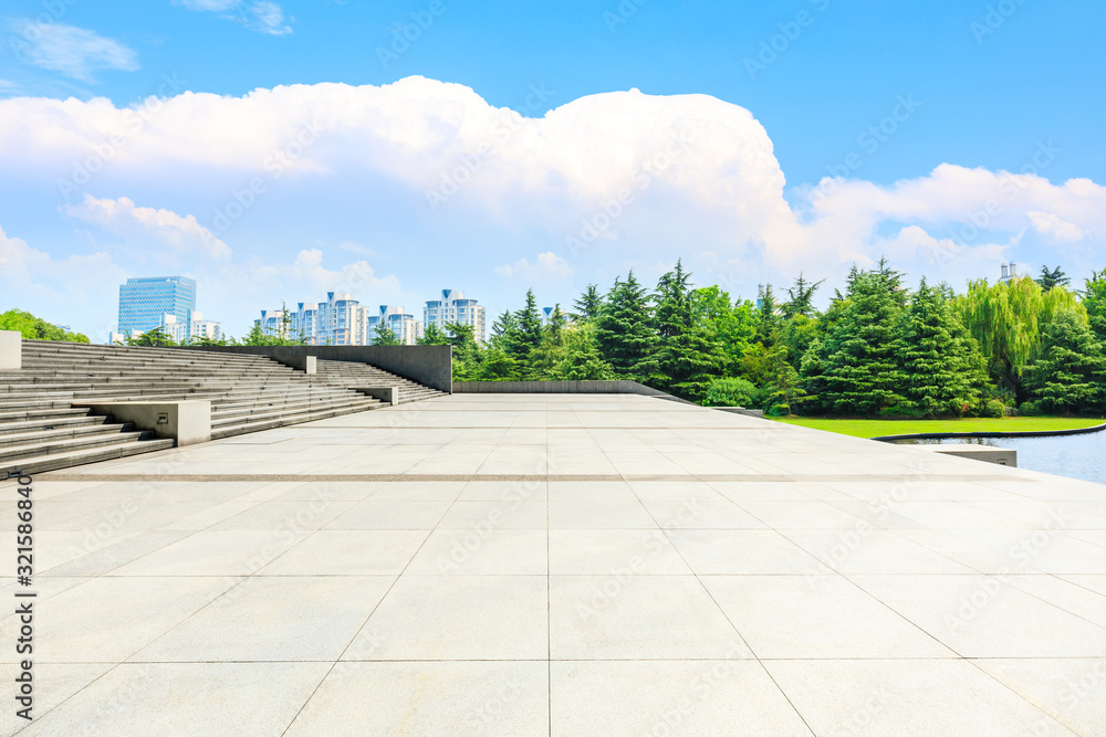 Empty square floor and building with forest under blue sky