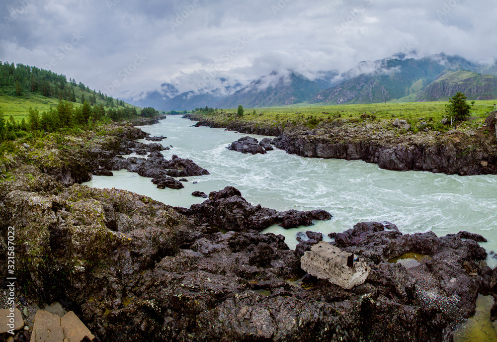 The Katun River in the Altai Mountains. Stormy stream in the rocky shores. Low cloud cover, natural light.