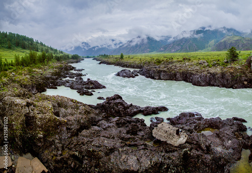 The Katun River in the Altai Mountains. Stormy stream in the rocky shores. Low cloud cover, natural light.