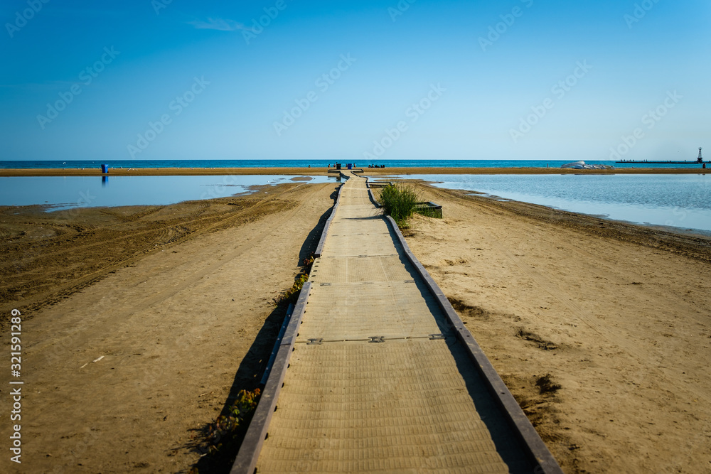 A deserted beach with walkway leading off to the distance