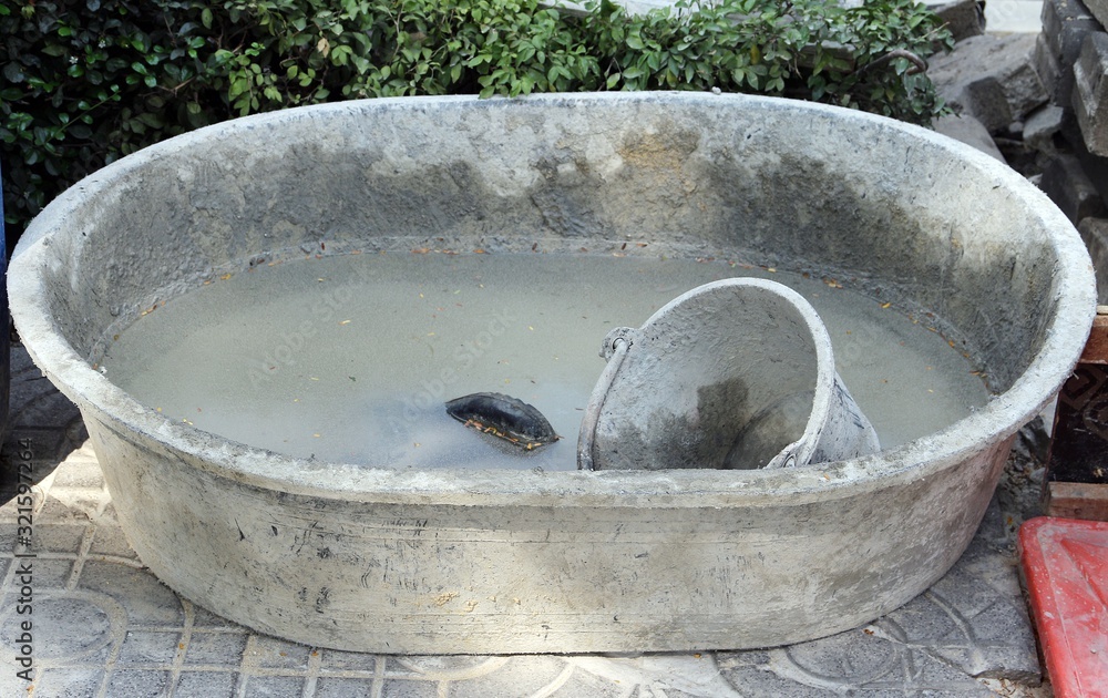 Fototapeta premium Cement mixing tub full with dirty water after finished task