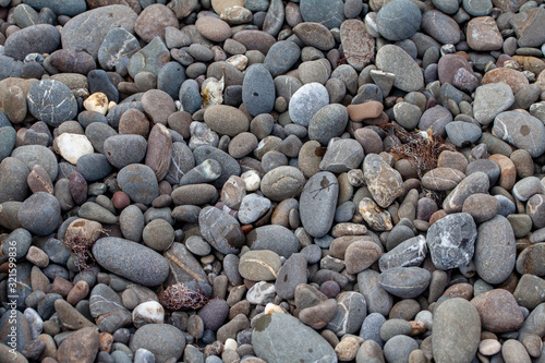 sea pebbles colored granite on the beach background stones. The shore of the beach with sand and pebbles washed by the waves of the sea.