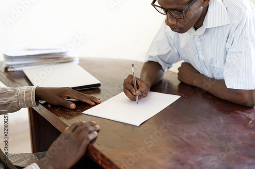 First day of work for this African young entrepeneur signing his contract on desk in boss's office photo