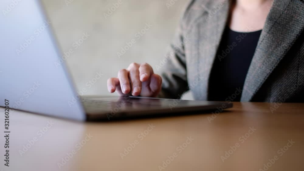 A woman touching on laptop computer touchpad on wooden table A woman touching on laptop computer touchpad on wooden table