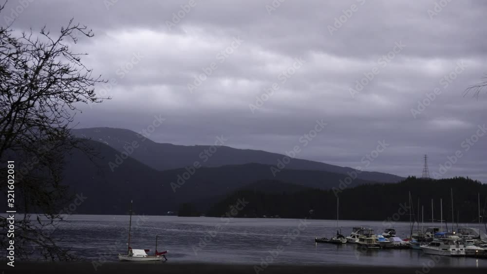 The view of the vast mountains and small boats in the sea at the skirts of it during a cloudy daytime weather.