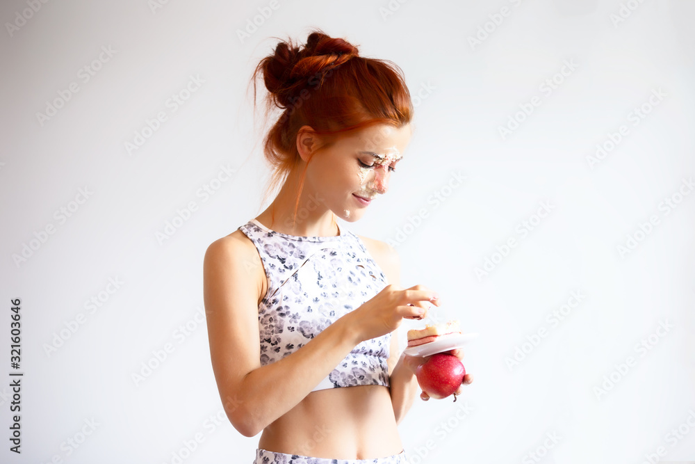 red hair women eating cake and apple on diet against white background red hair women eating cake and apple on diet against white background