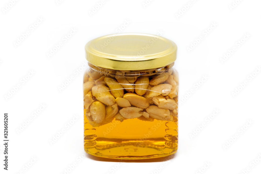 Glass jar with honey and peanuts on white background Glass jar with honey and peanuts on white background