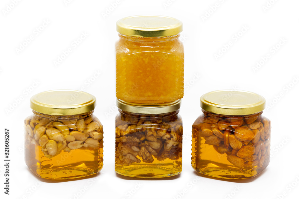 Pyramid of glass jars with honey with nuts and lemon on white background Pyramid of glass jars with honey with nuts and lemon on white background