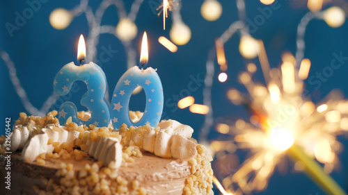 Birthday cake with 30 number candles and burning sparkler on blue backgraund. Close-up