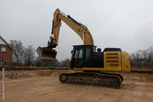  a building site there is a yellow excavator preparing the ground for foundations