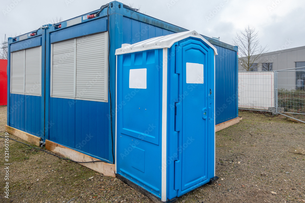 Naklejka premium a construction site a blue construction site toilet stands next to a blue container