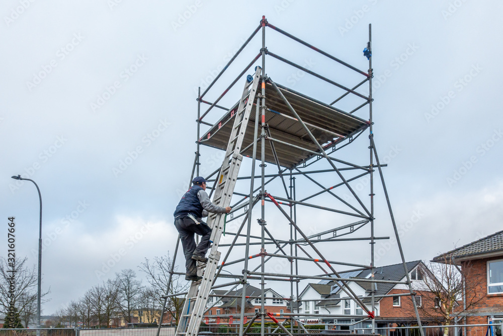 man climbs onto scaffolding on an extension ladder man climbs onto scaffolding on an extension ladder