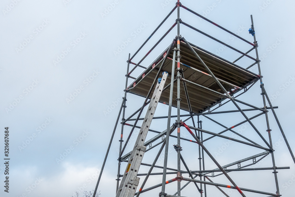 man climbs onto scaffolding on an extension ladder