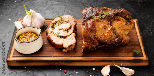 Fototapeta Naklejka Na Ścianę i Meble -  Roast pork meat roll  with herbs and spices on black stone table.