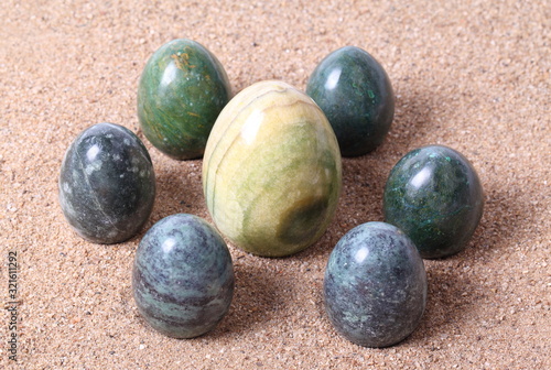 Set of green onyx egg on sand background.