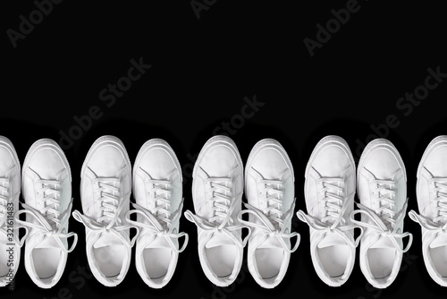 Short white low brigt sneakers on a black background. 