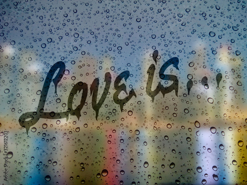 raindrops on the glass. inscription on wet glass: love is...
