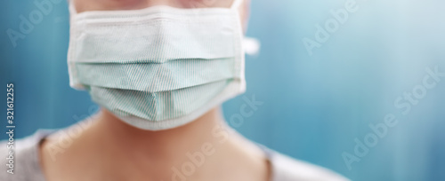 Tela young woman in medical face protection mask indoors on blue background