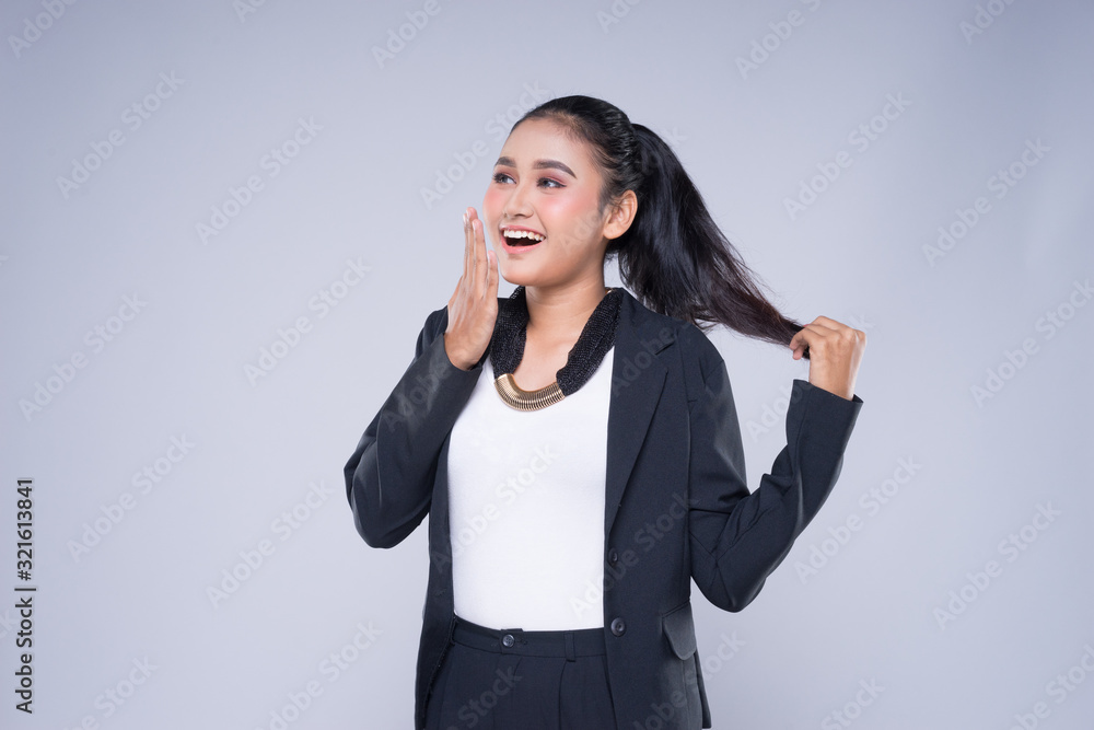 An attractive woman wearing business attire with gestures towards copyspace area isolated on grey. Good for manipulation works for technology, transportation, business or finance theme. An attractive woman wearing business attire with gestures towards copyspace area isolated on grey. Good for manipulation works for technology, transportation, business or finance theme.
