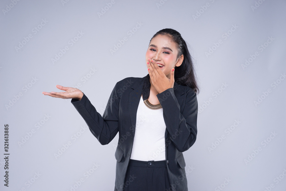 An attractive woman wearing business attire with gestures towards copyspace area isolated on grey. Good for manipulation works for technology, transportation, business or finance theme. An attractive woman wearing business attire with gestures towards copyspace area isolated on grey. Good for manipulation works for technology, transportation, business or finance theme.