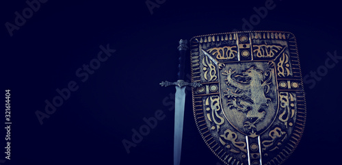 photo of shield knight armor and sword over dark background. Medieval period concept