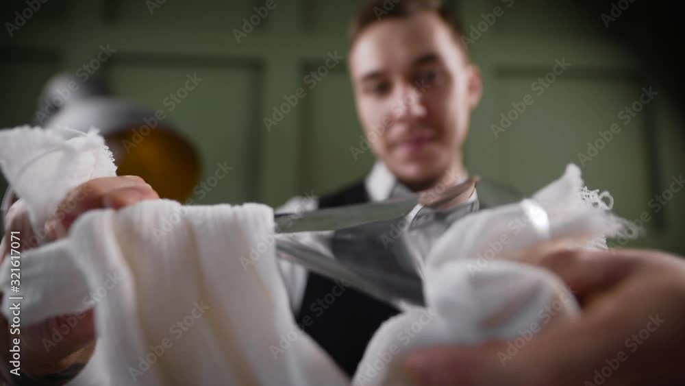 A male bartender rubs a transparent glass. A male bartender rubs a transparent glass.