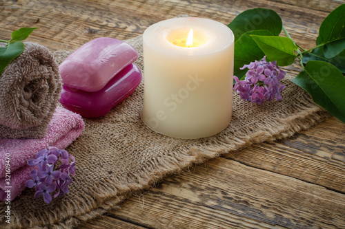 Towel  soap  candle and lilac flowers on wooden background.