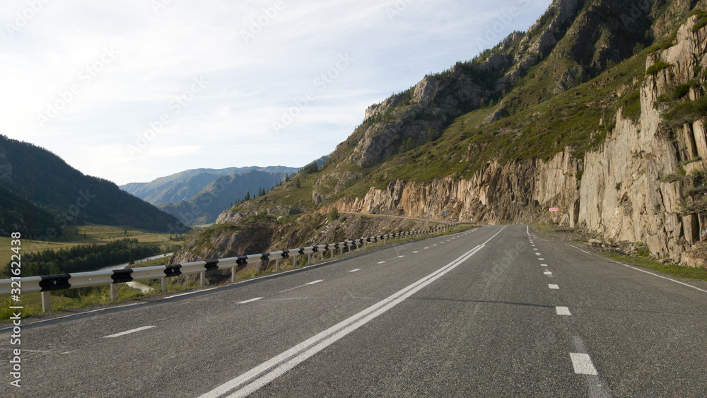 Fototapeta premium Beautiful flat empty asphalt road among the mountains. Accurate road markings. Traffic management in hard-to-reach places. Travel to Russia