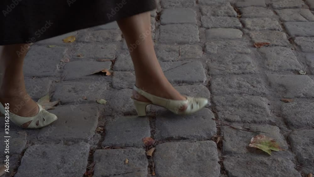 A sommotion, -pavemant and woman feet going from left to right A sommotion, -pavemant and woman feet going from left to right