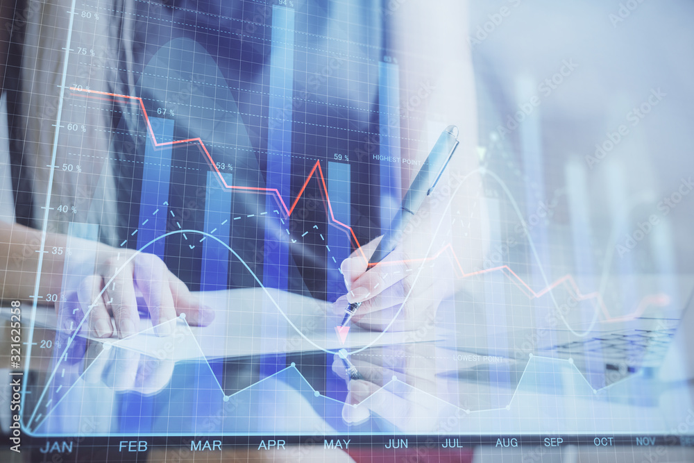 A woman hands writing information about stock market in notepad. Forex chart holograms in front. Concept of research. A woman hands writing information about stock market in notepad. Forex chart holograms in front. Concept of research.