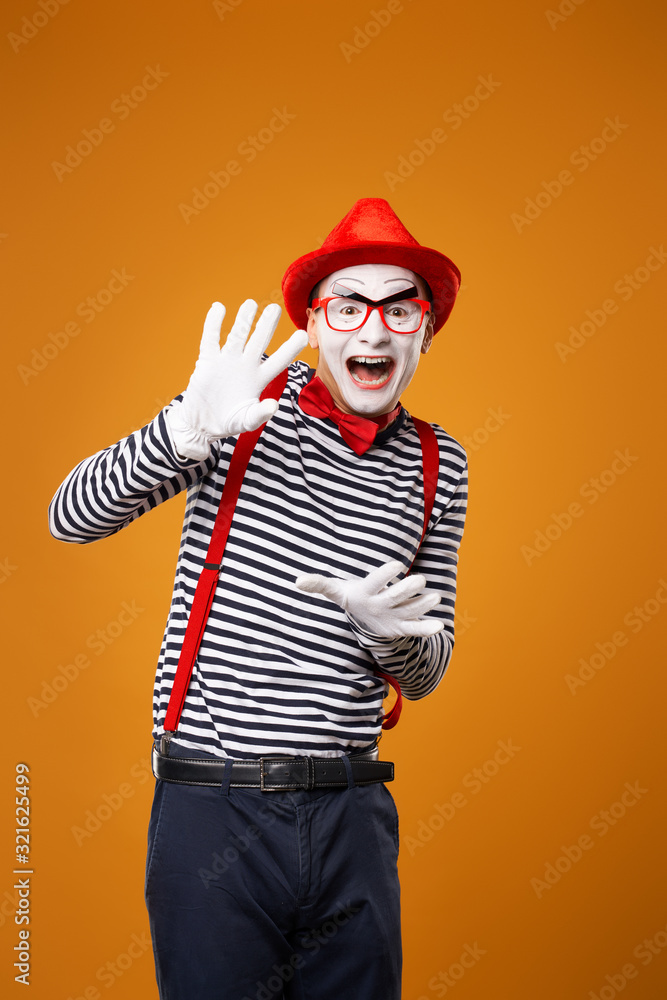 Happy mime man looking at camera in vest and red hat Isolated on orange background