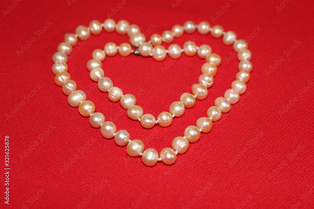 Heart made of pearls on a red background. Heart made of beads. Heart for valentines day. Heart made of pearls on a red background. Heart made of beads. Heart for valentines day.
