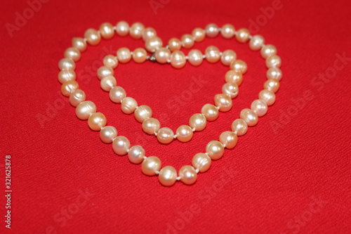 Heart made of pearls on a red background. Heart made of beads. Heart for valentines day.